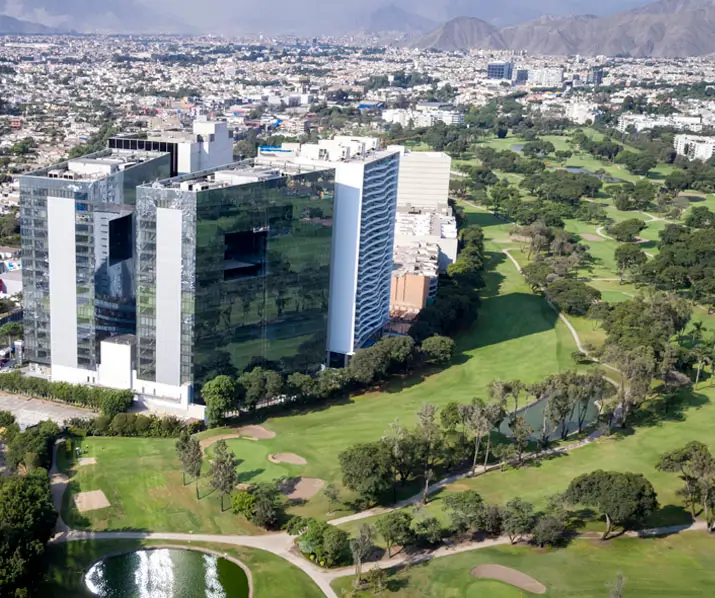 Vista aérea de un campo de golf en la ciudad, rodeado de edificios modernos y vegetación exuberante.