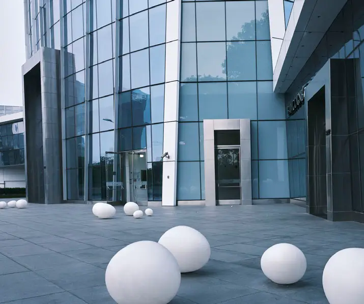 Edificio moderno con fachada de vidrio y esferas blancas decorativas en el acceso principal. Estilo arquitectónico contemporáneo.