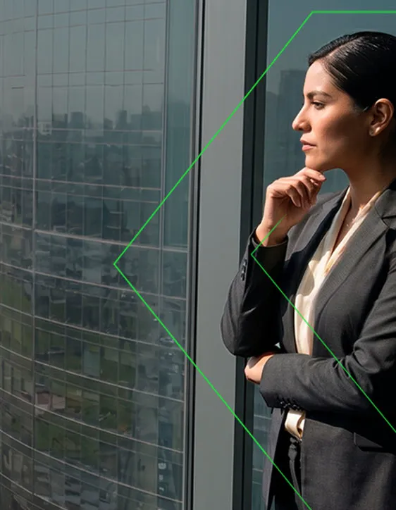 Mujer de negocios pensativa mira por ventana de oficina con vista a la ciudad, vestido formal y gesto reflexivo.