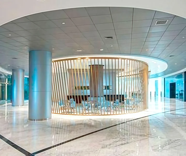Lobby moderno con iluminación suave, paredes de vidrio y separación de madera. Espacio elegante y minimalista.
