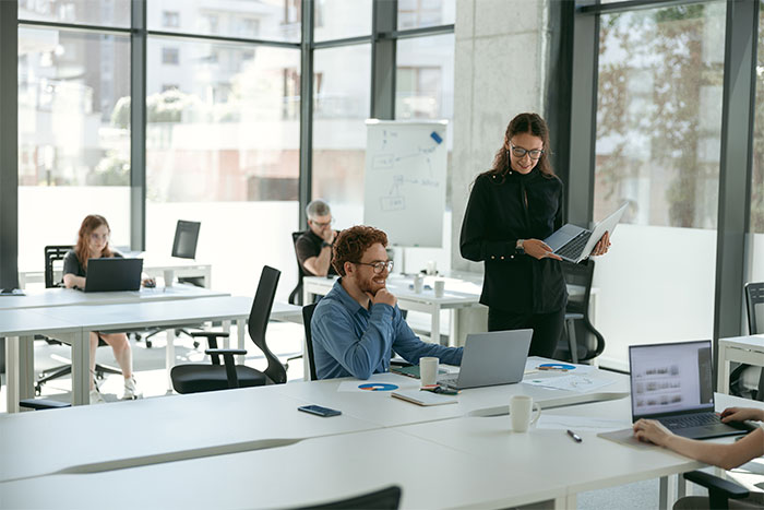 Espacio de trabajo moderno, con profesionales colaborando en laptops, destacando la interacción y la productividad.