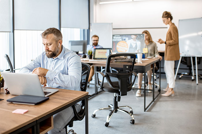 Oficina moderna con empleados trabajando en computadoras. Ambiente colaborativo.