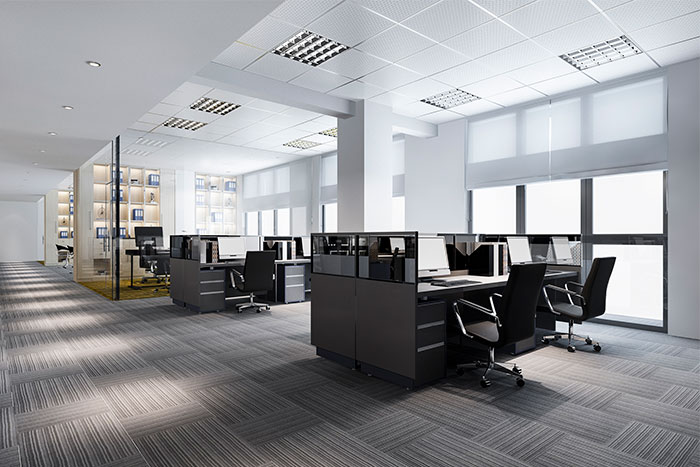 Espacio de oficina moderno con escritorios, sillas ergonómicas y ventanales que permiten la entrada de luz natural.