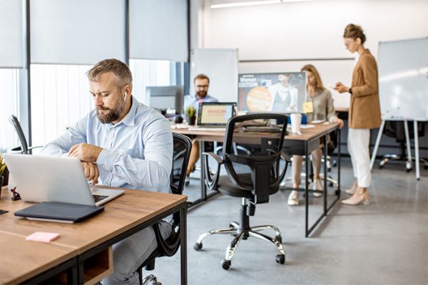 Oficina moderna con empleados trabajando en computadoras. Ambiente colaborativo.